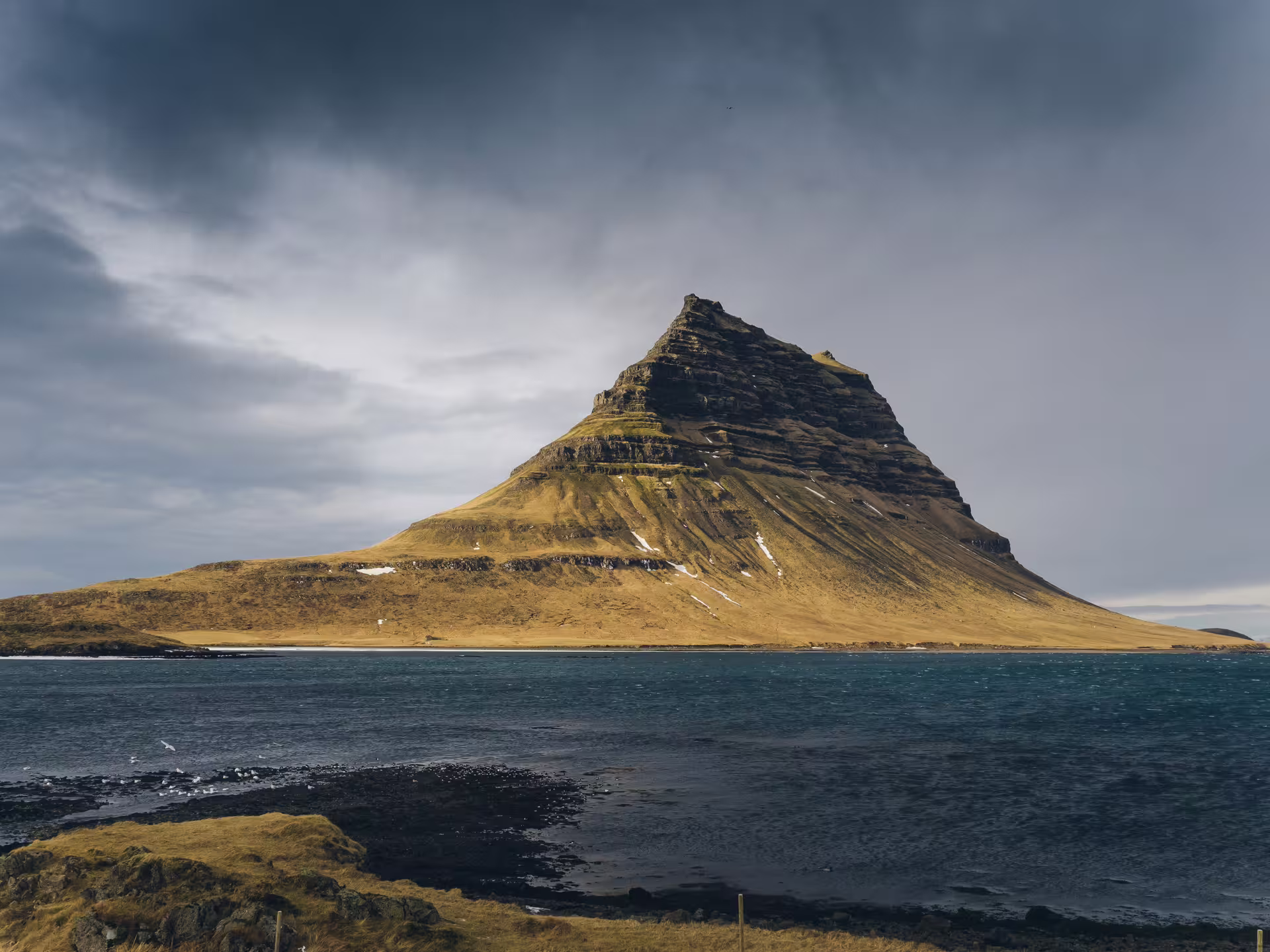 Iconic Kirkjufell mountain rising above the blue waters of Snaefellsnes Peninsula on a private day trip from Reykjavik Iceland