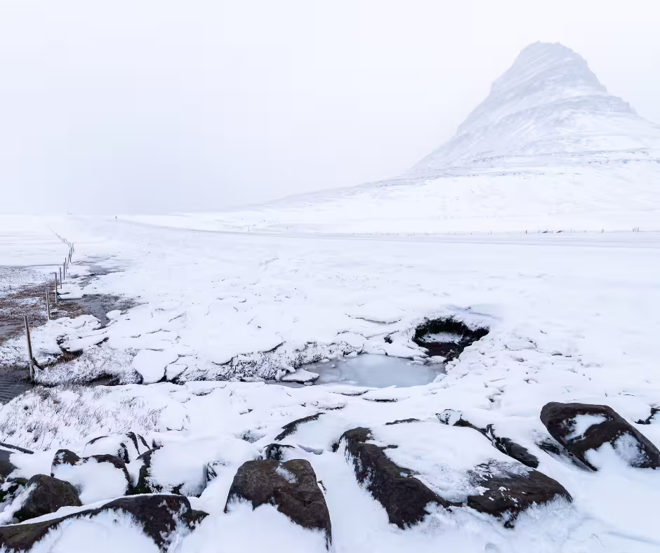 Kirkjufell mountain covered in snow with frozen landscape and rocks on Snaefellsnes Peninsula, Iceland