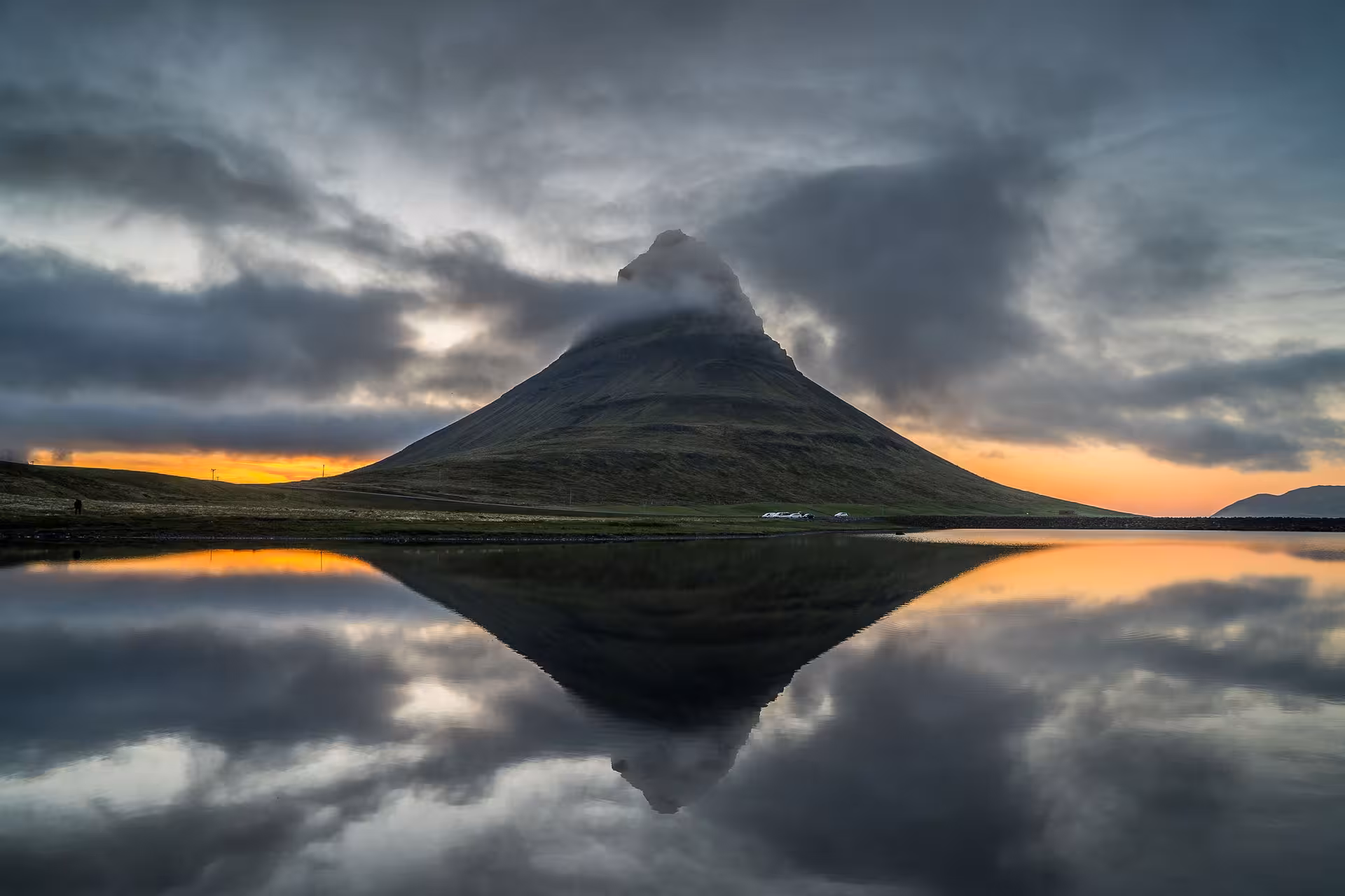 Kirkjufell mountain reflecting in calm water at sunset with dramatic clouds, Snaefellsnes Peninsula, Iceland