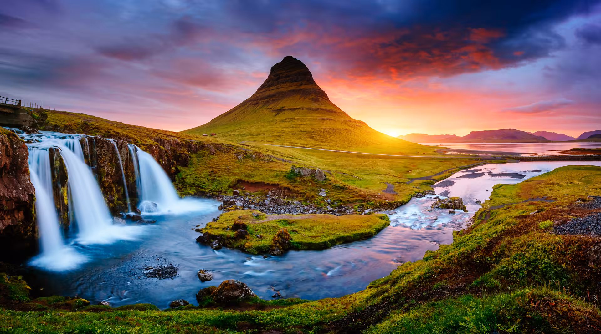 Kirkjufellsfoss waterfall and Kirkjufell mountain at sunset during Iceland ring road tour