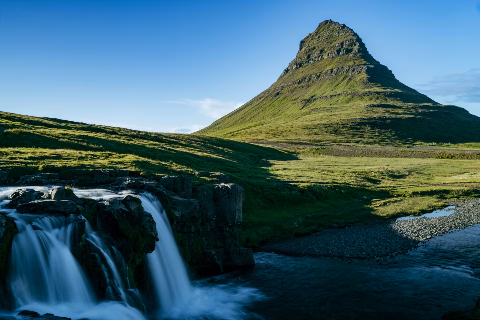 Kirkjufell mountain with cascading waterfall and green meadows on Snaefellsnes Peninsula, Iceland