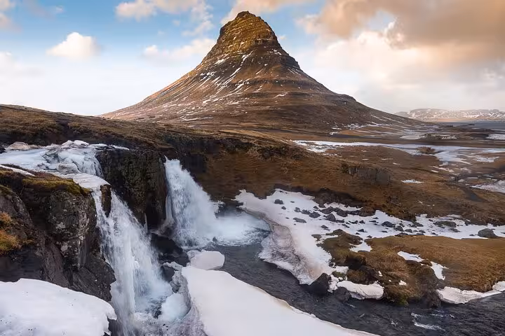 Kirkjufell mountain with waterfall and snow in Snaefellsnes Peninsula, West Iceland