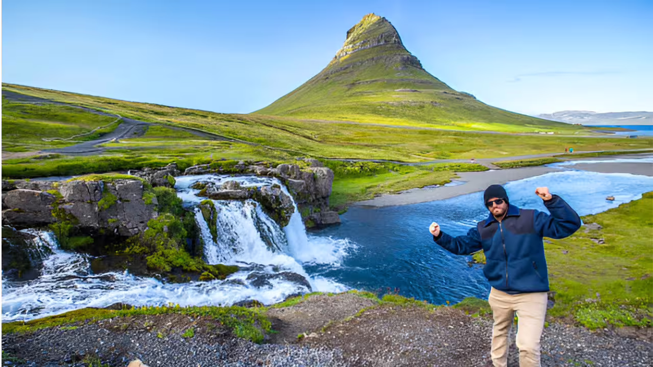 Tourist posing at Kirkjufell mountain waterfall on Snaefellsnes Peninsula Iceland