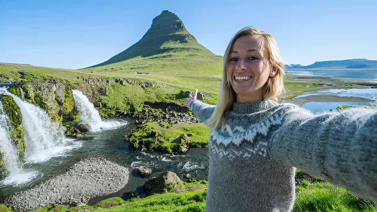 Woman taking selfie at Kirkjufell mountain with Kirkjufoss waterfall on Snaefellsnes Peninsula, Iceland