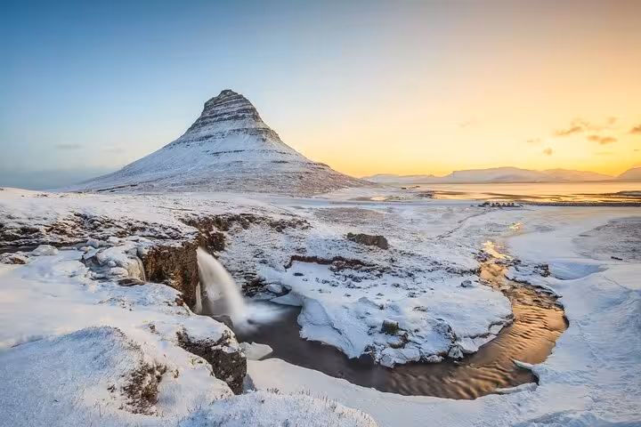 Snow-covered Kirkjufell mountain with waterfall at golden sunset in Snaefellsnes Peninsula, Iceland