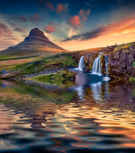 Kirkjufell mountain with cascading waterfalls reflecting in calm water at sunset, Snaefellsnes Peninsula, Iceland