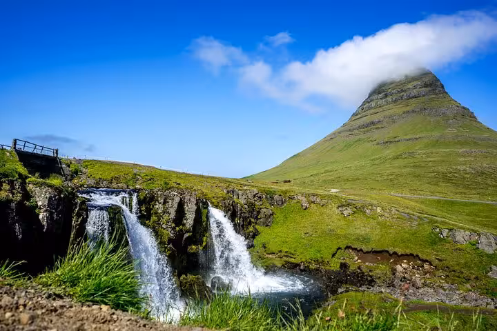 Kirkjufellsfoss waterfall with iconic Kirkjufell mountain and lush green landscape in Snaefellsnes, Iceland