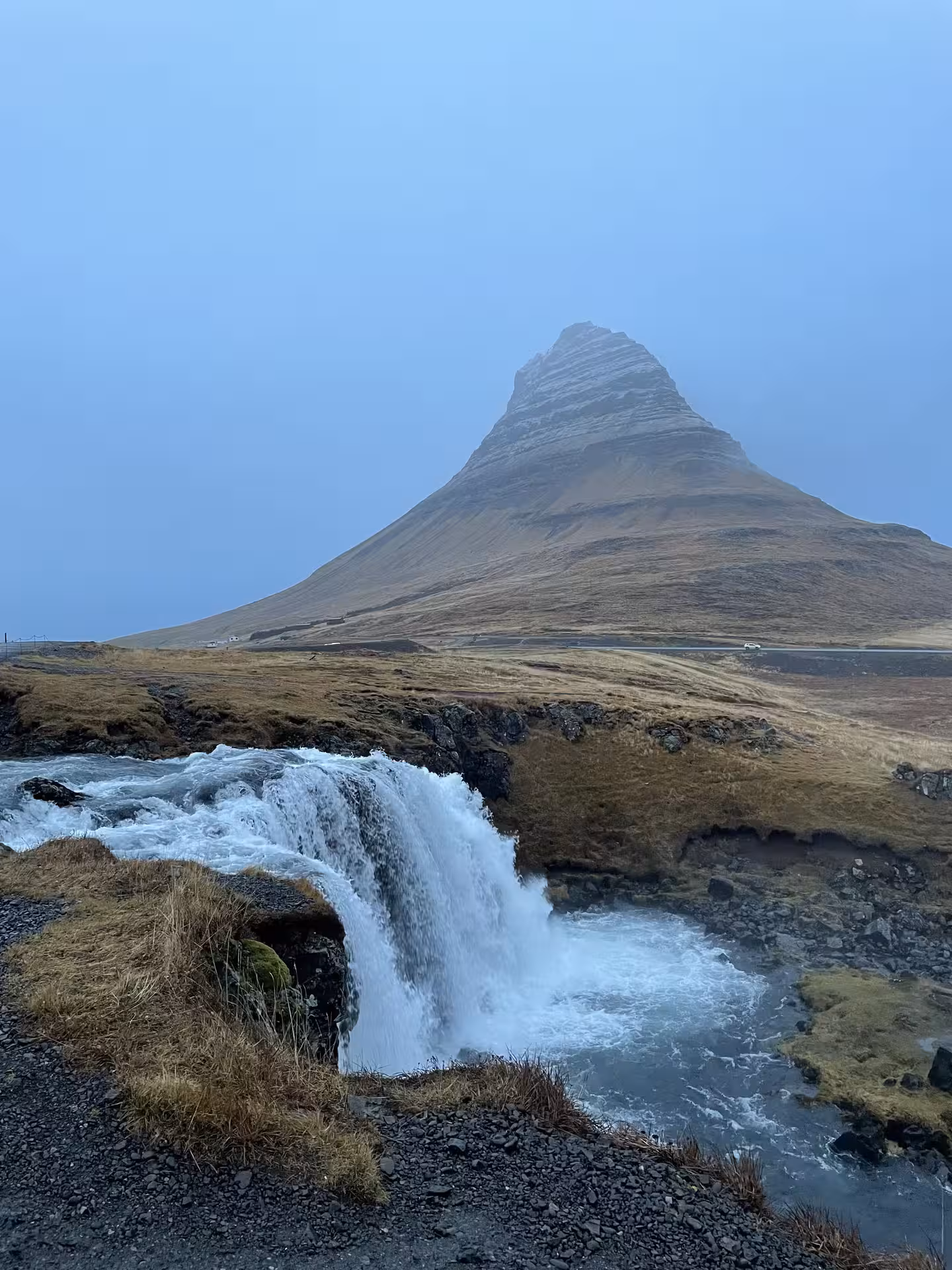 Kirkjufellsfoss waterfall with iconic Kirkjufell mountain peak in misty conditions, Snaefellsnes Peninsula, Iceland
