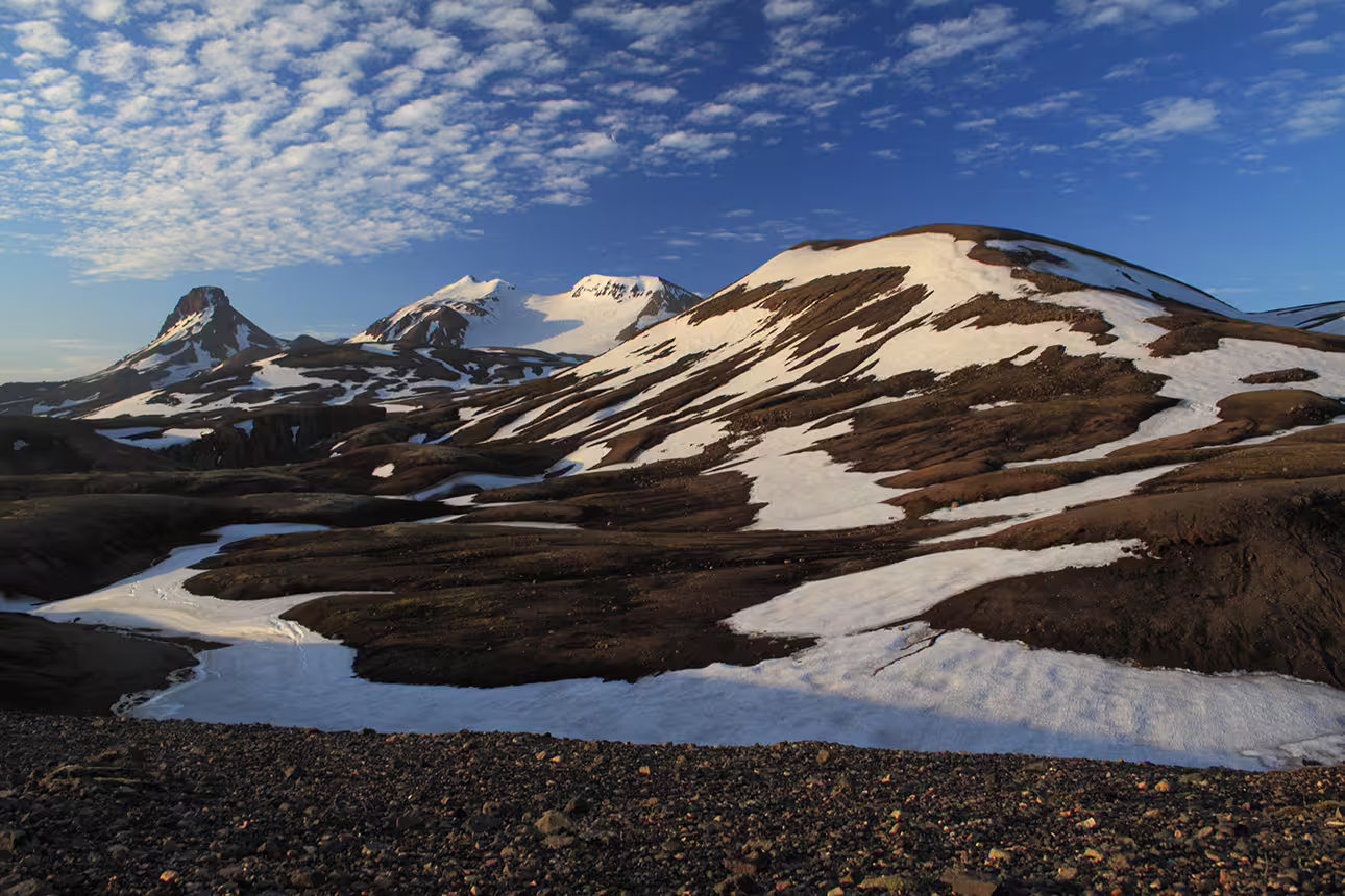 Snow-patched volcanic mountains under blue sky in Kjolur Highland Iceland
