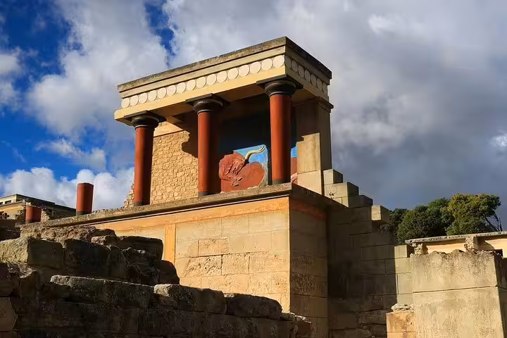 Reconstructed red columns and bull fresco at Knossos Palace on a private full-day tour from Heraklion with pickup