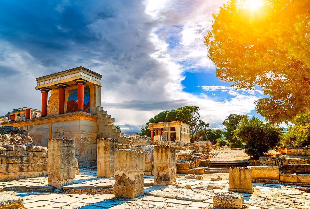 Knossos Palace ruins with red columns in sunlight, highlight stop on Crete full-day eco e-bike tour