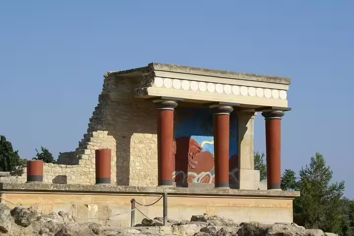 Explore the ancient architectural grandeur of Knossos Palace with vibrant frescoes and iconic red columns on a luxury adventure.