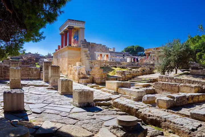 Panoramic view of Knossos Palace ruins under a bright blue sky, highlighting ancient Minoan civilization.