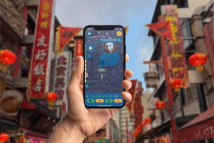 Hand holding smartphone with interactive map app in Kobe Chinatown street with red lanterns