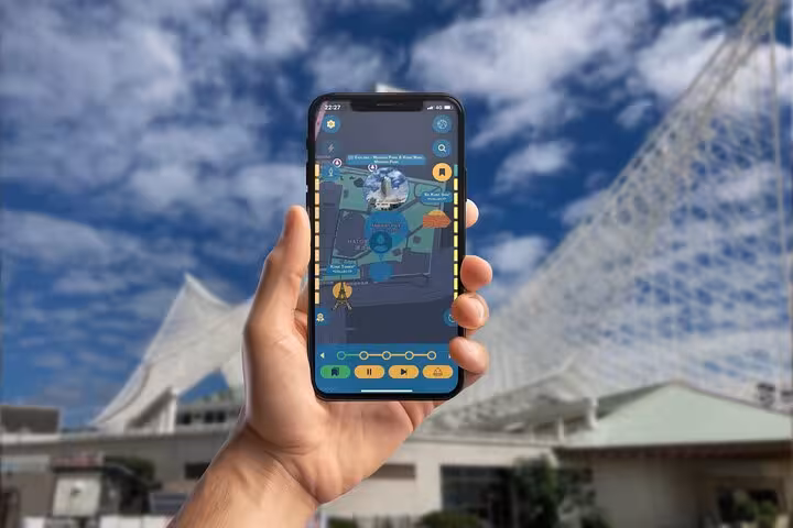 Hand holding smartphone displaying interactive map app for self-guided walking tour in Kobe, Japan