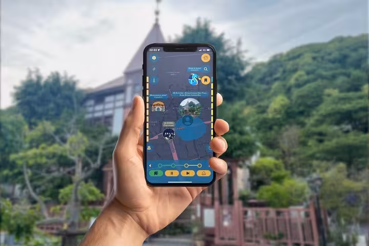 Hand holding smartphone displaying interactive mobile game map for self-guided walking tour in Kobe, Japan
