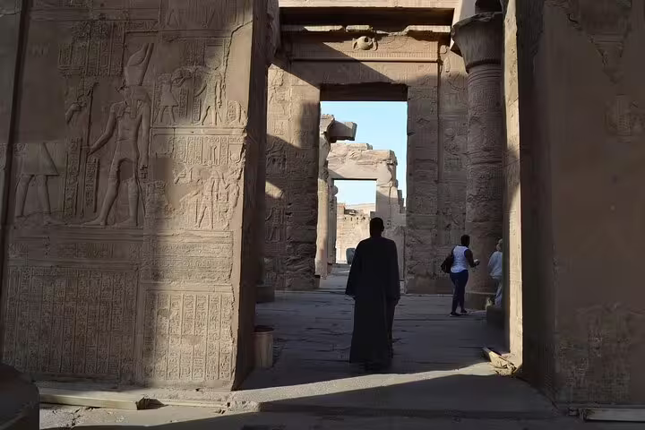 Visitors walking through carved stone gateway at Kom Ombo Temple, Luxor day trip to Edfu and Kom Ombo