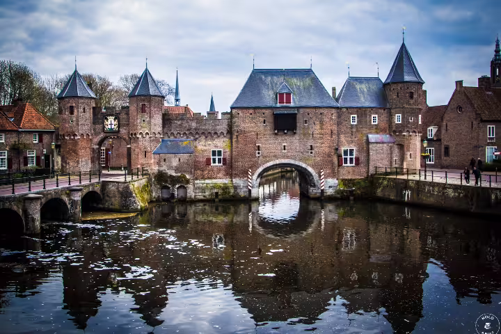 Historic Koppelpoort gate reflecting in Amersfoort canal, a scenic highlight of the walking tour from Amsterdam by train.