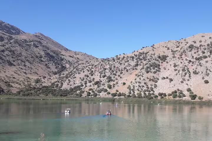 Serene view of Kournas Lake in West Crete with boats against a backdrop of rugged hills, ideal for a private Chania and Rethymno tour.