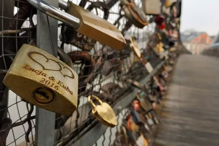 Love locks on a bridge fence in Krakow, with engraved padlock reading Lucja & Kuba 2016