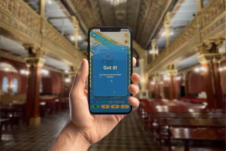 Hand holding smartphone displaying 'Got it!' scavenger hunt app in ornate Krakow Jewish Quarter building
