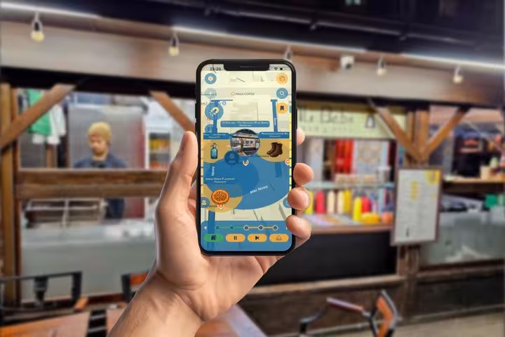 Hand holding smartphone displaying interactive map app for self-guided walking tour in Krakow market