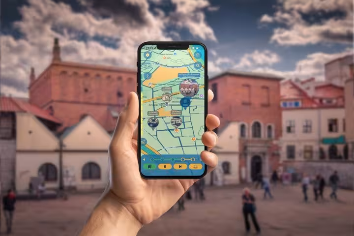Hand holding smartphone displaying interactive map for Jewish Quarter walking tour in Krakow city square
