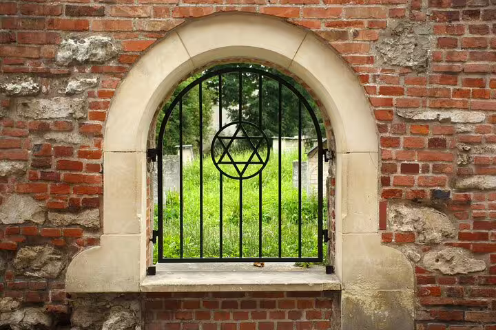 Iron gate with Star of David in arched brick wall leading to Jewish cemetery in Krakow