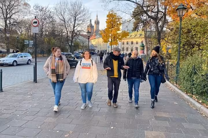 Tour group strolling through Krakow's picturesque streets, surrounded by autumn foliage and historic architecture.