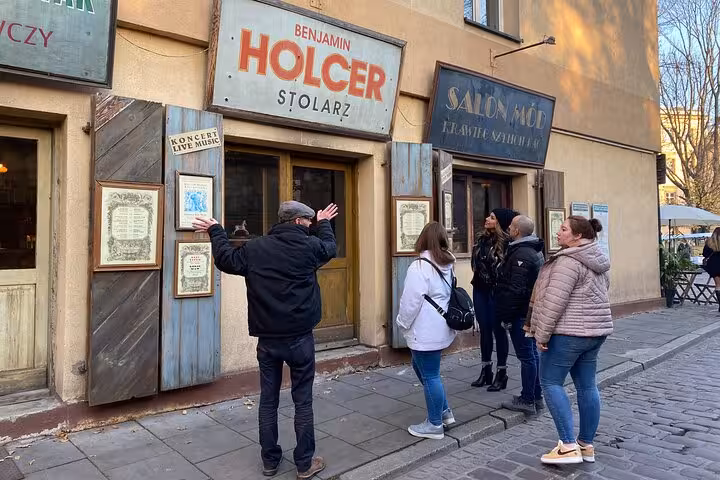 Visitors engaging with a guide outside a charming vintage shop in Krakow's old city, highlighting cultural heritage.