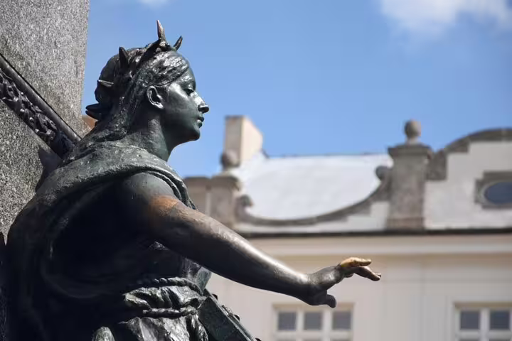 Bronze statue of a crowned female figure with outstretched hand in Krakow Old Town square