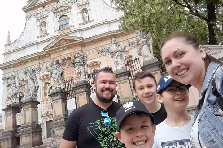 Family smiling in front of ornate Baroque church facade during Krakow Old Town walking tour