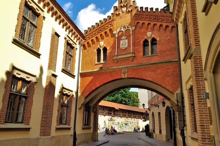 Historic red brick Gothic arch gateway on a cobblestone street in Krakow Old Town