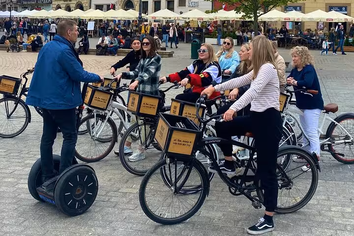 Cyclists gather around a guide in Krakow's vibrant Old Town for an engaging bike tour.