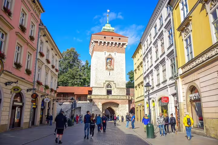 Tourists walking toward St. Florian's Gate tower on Florianska Street in Krakow Old Town