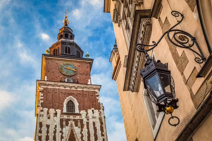 Town Hall Tower with golden clock face and ornate street lantern in Krakow Old Town