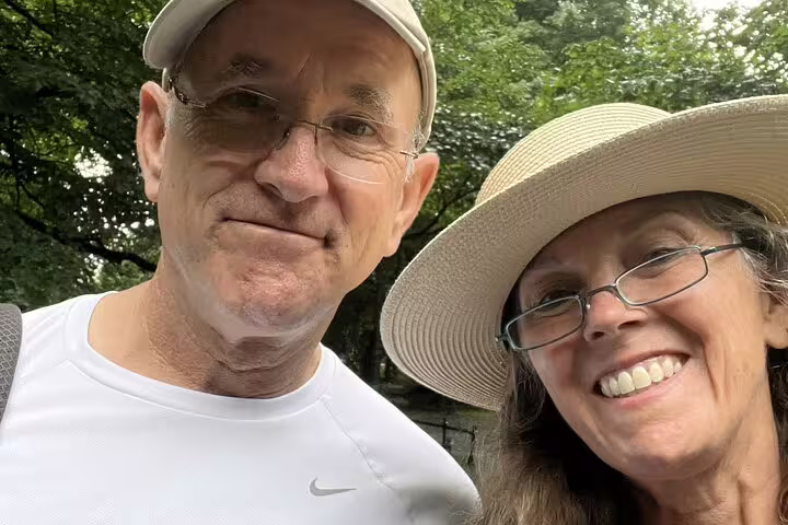 Two older adults smiling outdoors during a guided walking tour in a park setting