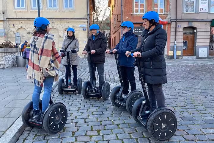 Tour group on Segways in Krakow's charming cobblestone streets, wearing helmets.