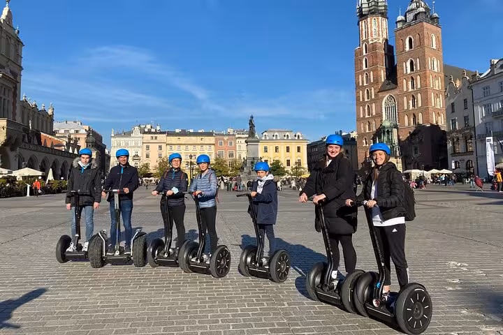 Visitors on Segways in Krakow's Main Market Square with St. Mary's Basilica towering behind.