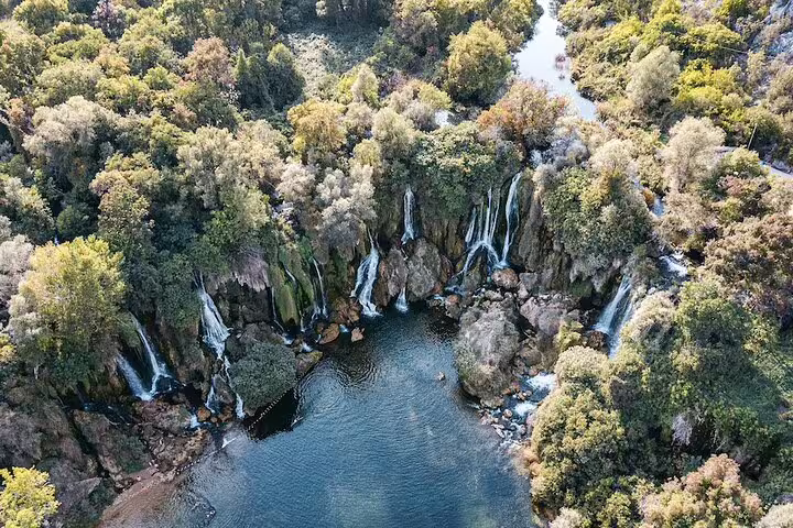 Aerial view of Kravice Waterfalls lagoon in Bosnia, lush forest cliffs on the Mostar day tour