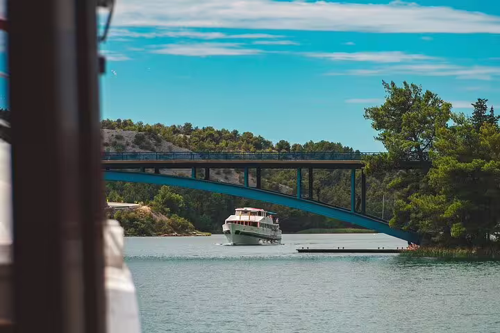 Boat cruise on the Krka River passing under bridge en route to Krka Waterfalls tour with swimming stop
