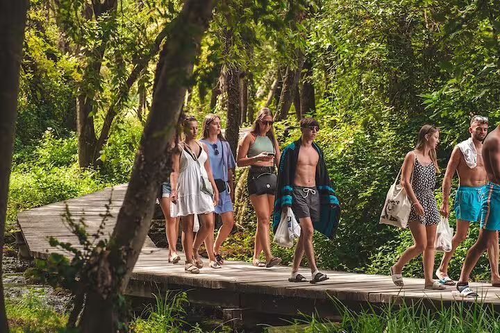 Visitors walking the wooden boardwalk in Krka National Park on a scheduled waterfalls tour from Split