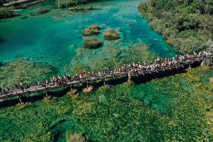 Aerial view of tourists on a wooden boardwalk over turquoise pools at Krka Waterfalls on a scheduled tour