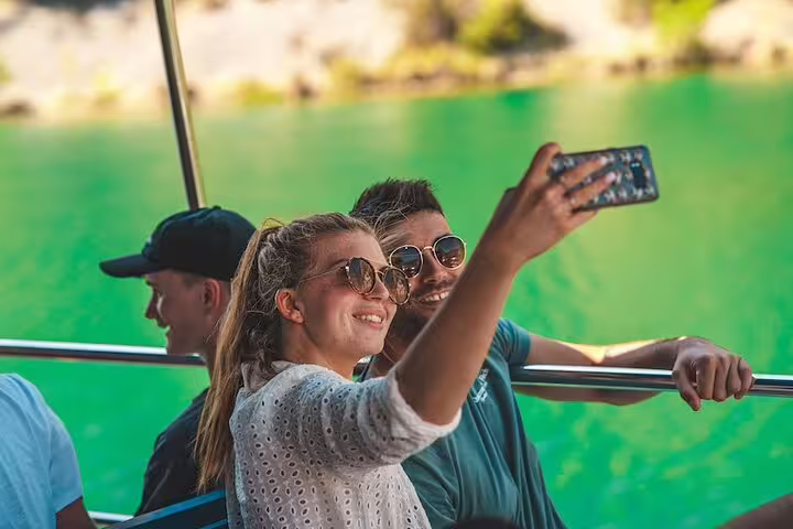 Guests taking a selfie on Krka boat cruise with emerald water behind, part of Krka Waterfalls tour
