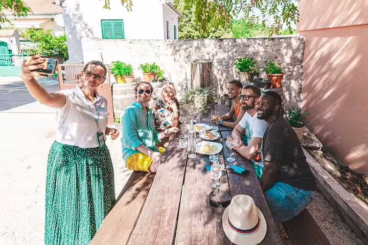 Guests enjoy Dalmatian food and wine tasting after Krka Waterfalls tour, taking a selfie at a rustic table