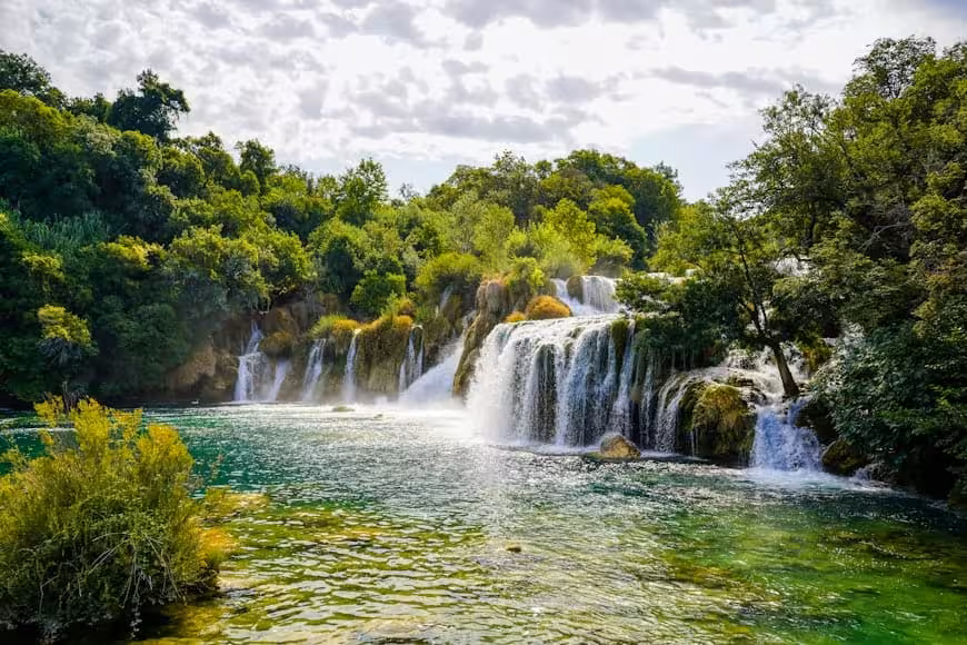 Panoramic Krka Waterfalls group tour scene with emerald river and multiple cascades in Krka National Park
