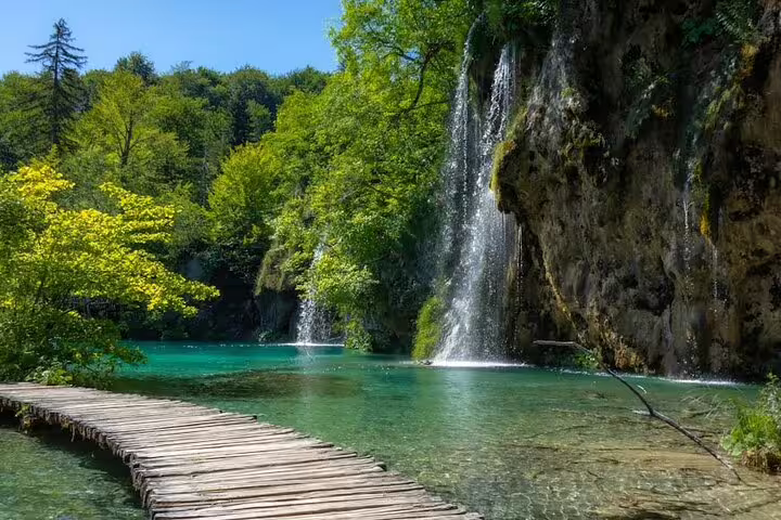 Wooden boardwalk by emerald lake and waterfall in Plitvice Lakes, Split to Plitvice guided group adventure