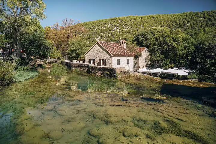 Stone house by clear Krka River in Krka National Park on a private Krka Waterfalls tour from Split