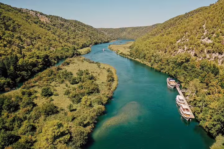 Scenic Krka River canyon with docked boats, part of a private Krka Waterfalls tour with optional wine tasting