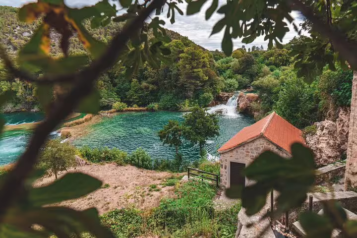 Scenic Krka Waterfalls viewpoint with turquoise lake, small stone house and cascades in Croatia